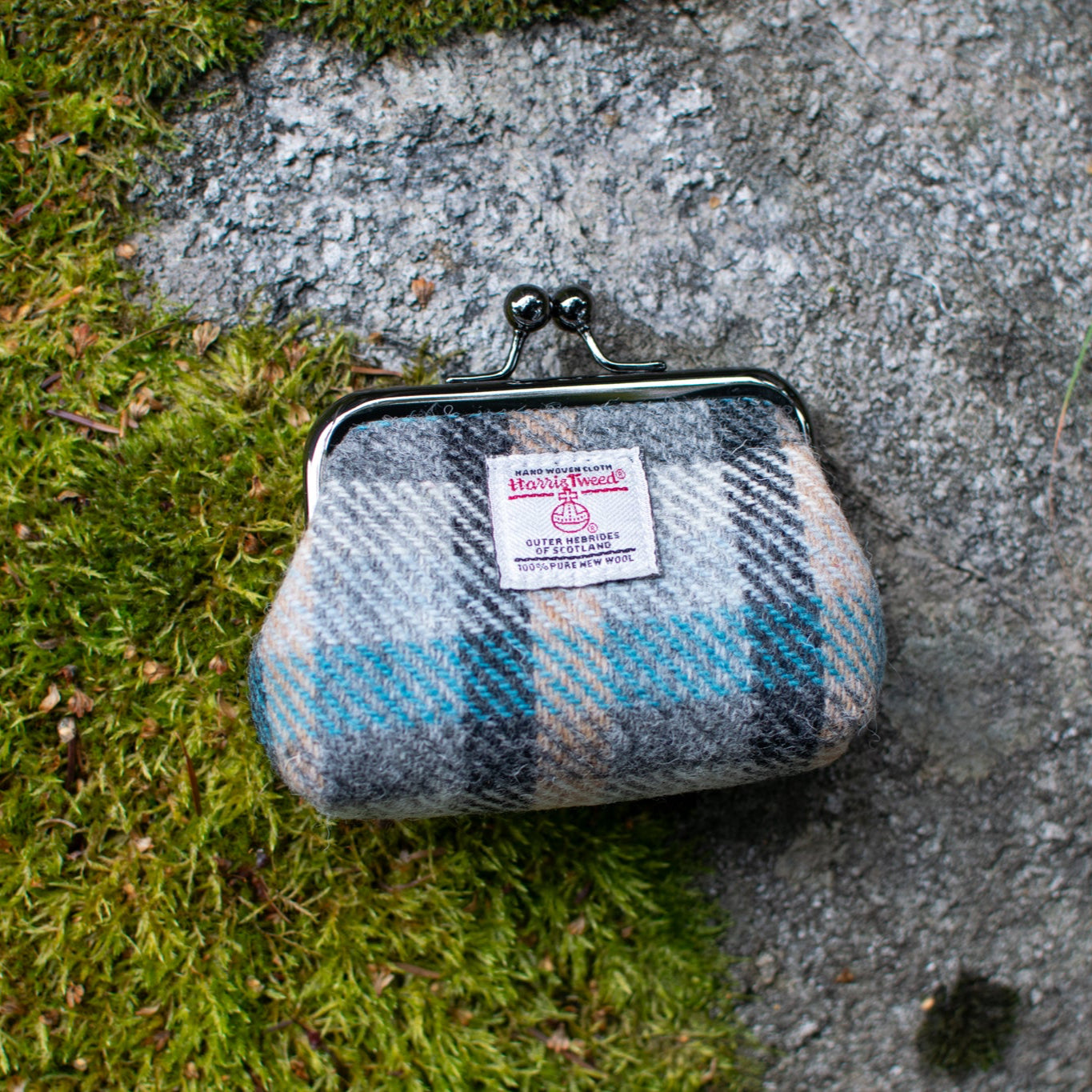 Plaid coin purse with a label on a stone surface and grass