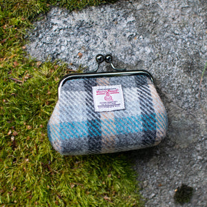 Plaid coin purse with a label on a stone surface and grass