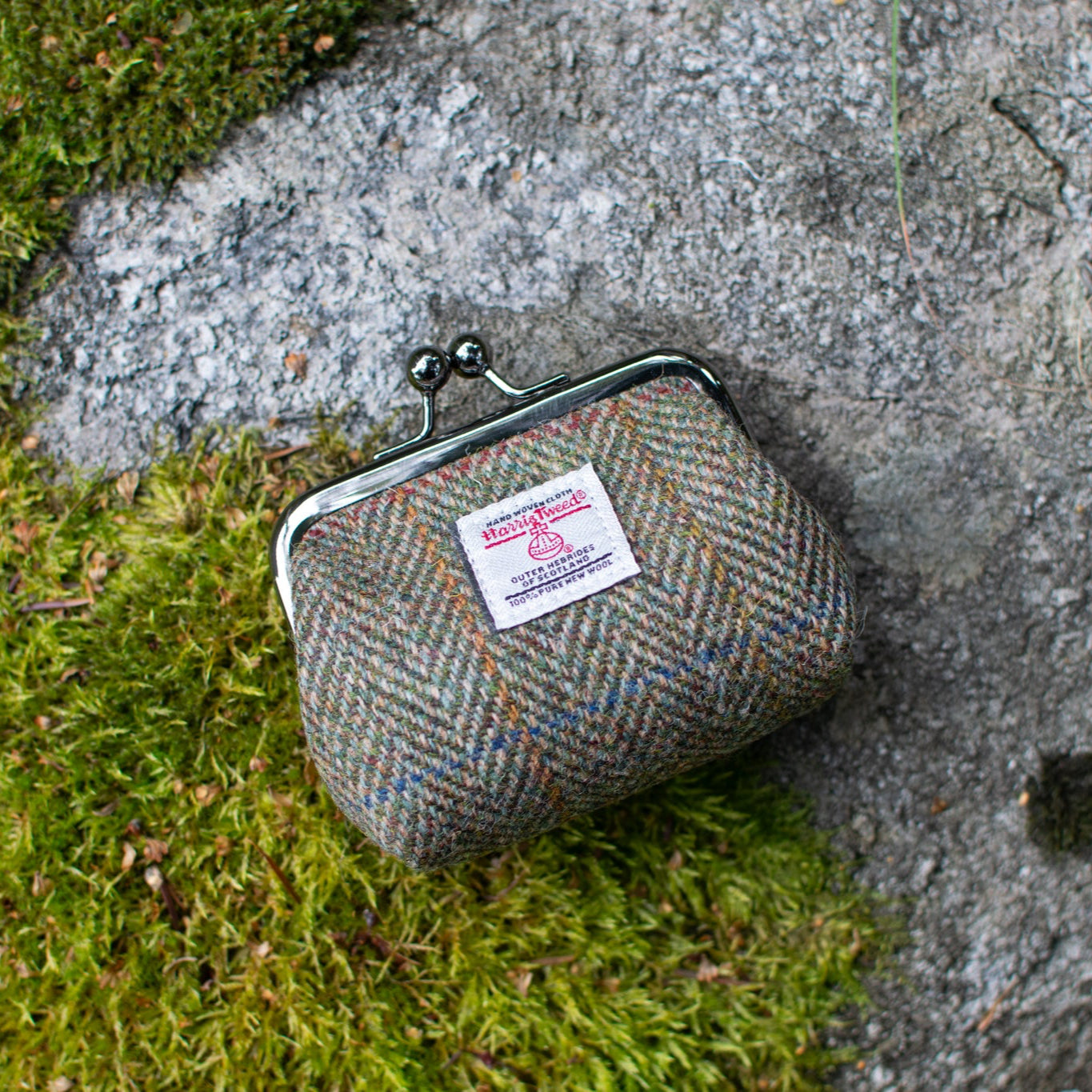 Textile coin purse on a stone surface with grass