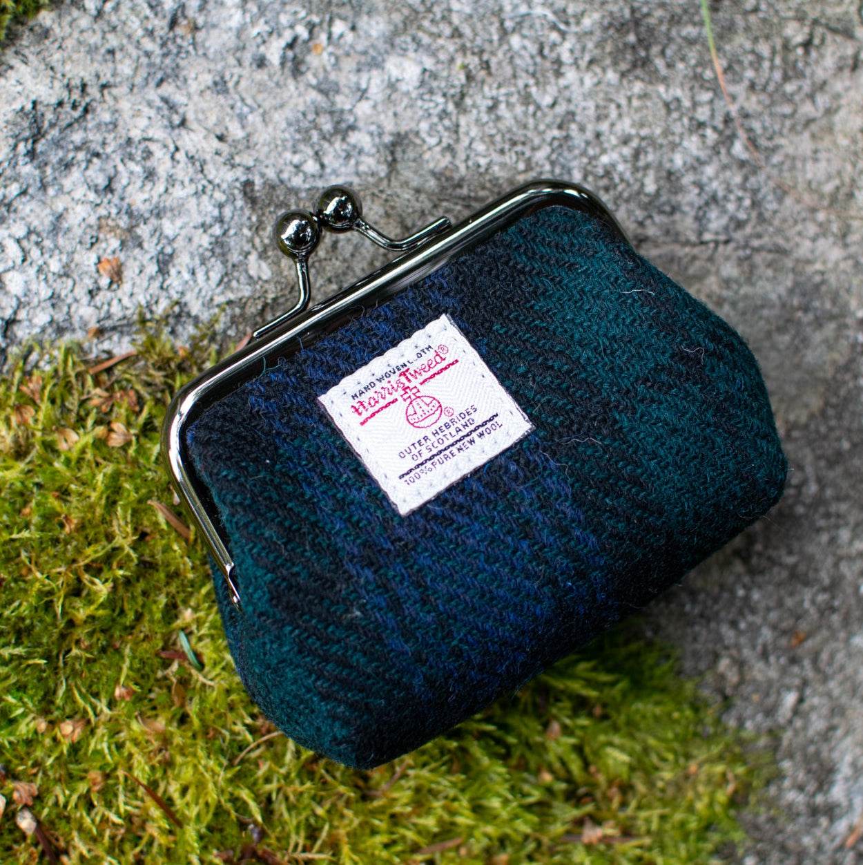 Blue textured pouch with a label on a stone surface with moss