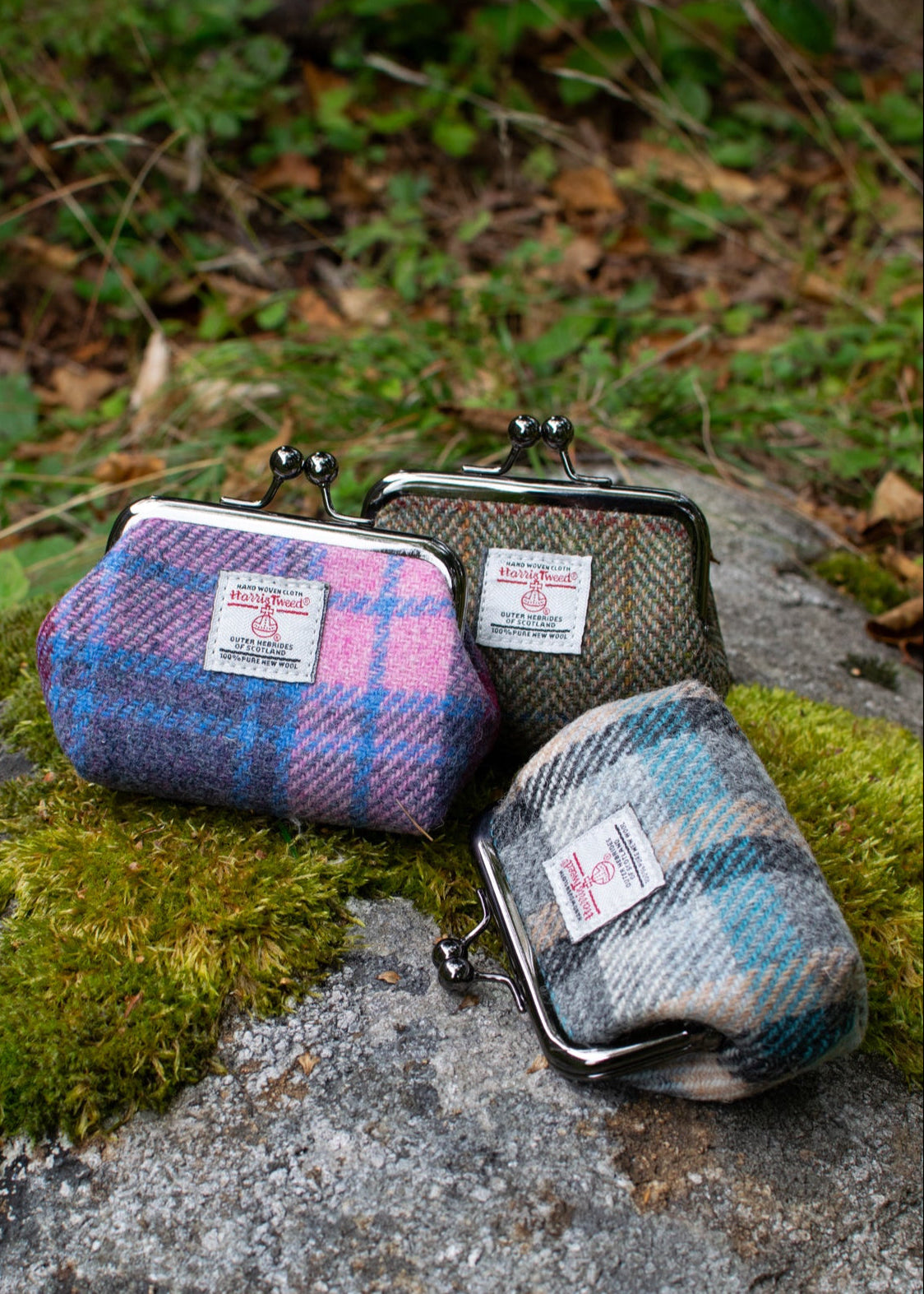 Three plaid coin purses on a rock with a natural background
