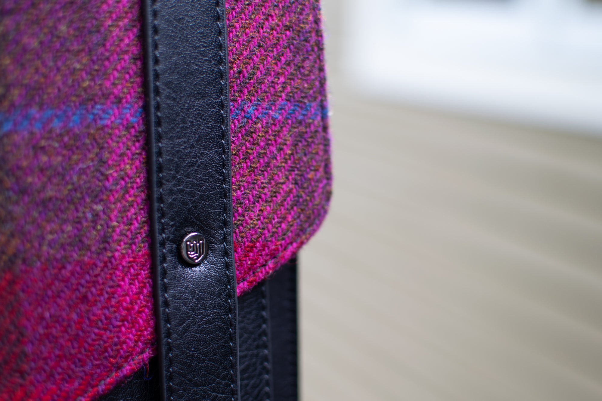 Close-up of a pink textured fabric with a black strap and button on a blurred background