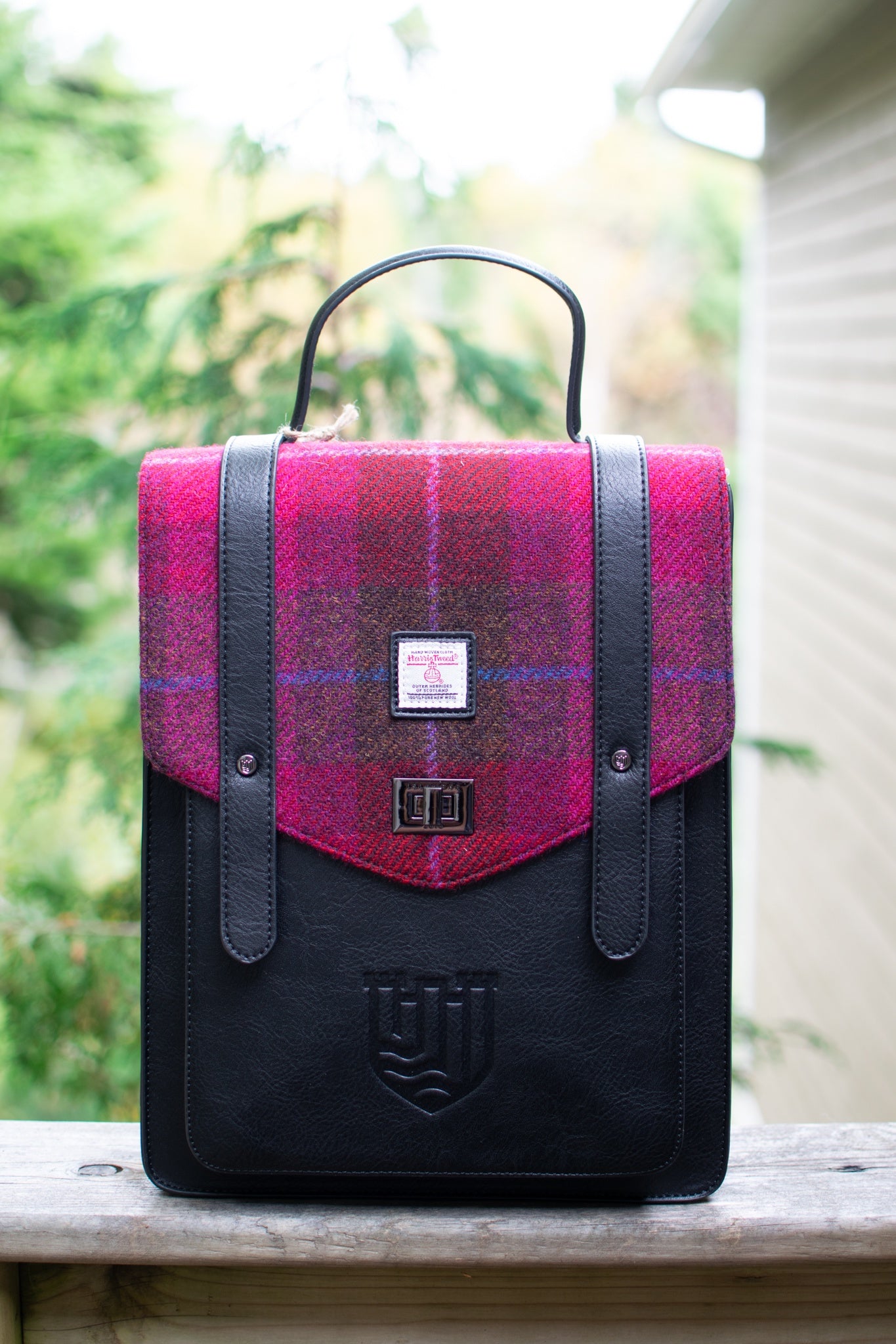 Pink and black plaid bag with a visible brand logo on a wooden surface.