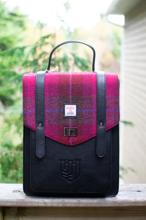 Pink and black plaid bag with a visible brand logo on a wooden surface.