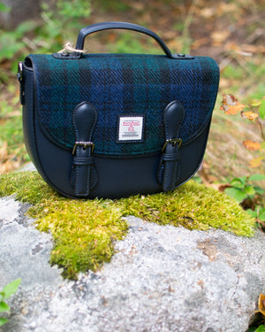 Blue plaid bag with black accents on a rock in a natural setting