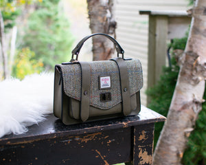 Green handbag with a visible brand logo on a wooden surface outdoors.