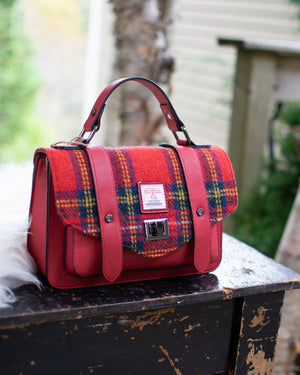 Red plaid handbag on a wooden surface with a blurred natural background