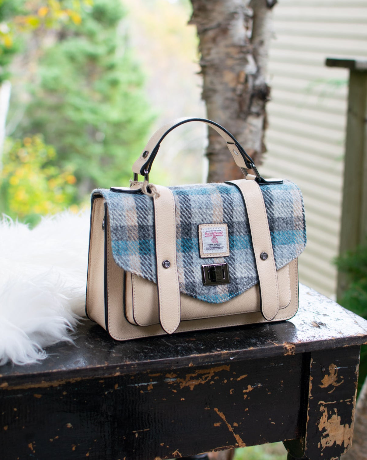 Handbag with plaid pattern on a wooden table outdoors