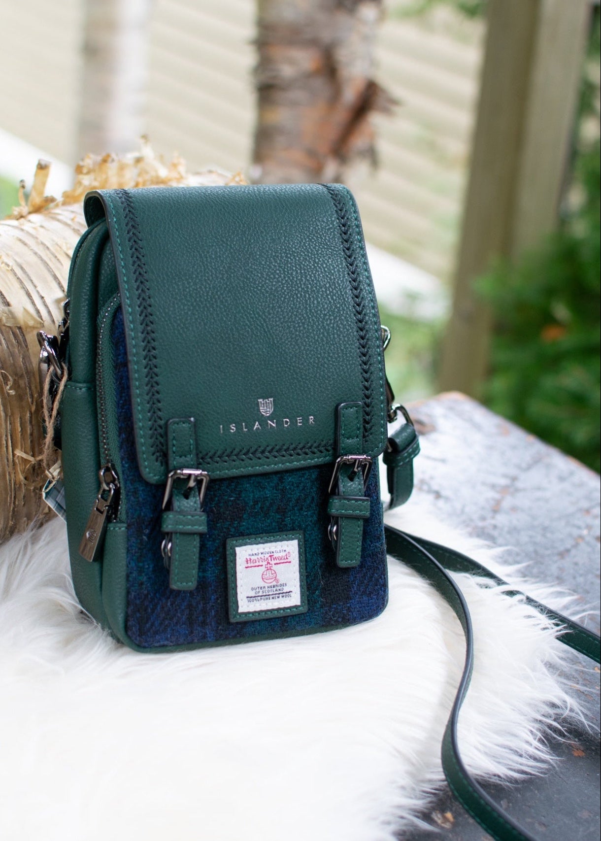 Green crossbody purse with straps on a white surface with blurred natural background