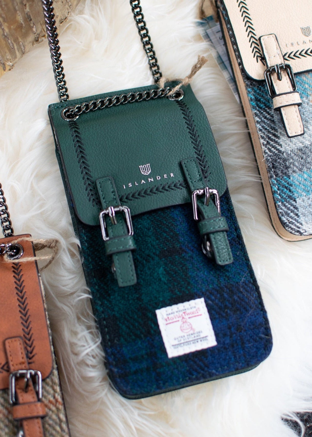 Green and blue plaid crossbody bag with chain strap on a textured surface